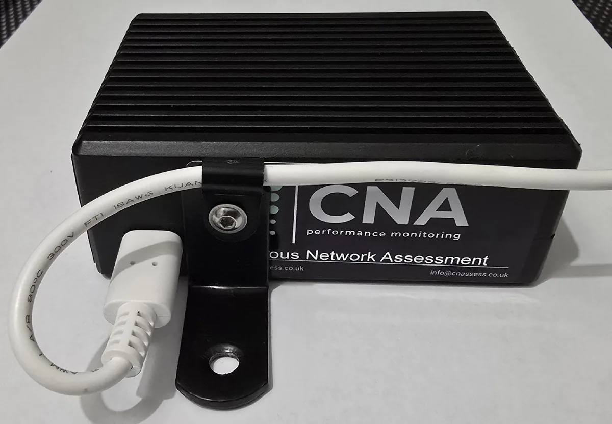 A CNA ModelB sensor: a black finned enclosure with an L-shaped bracket screwed to one end and the white power cable held against it by a cable clip.